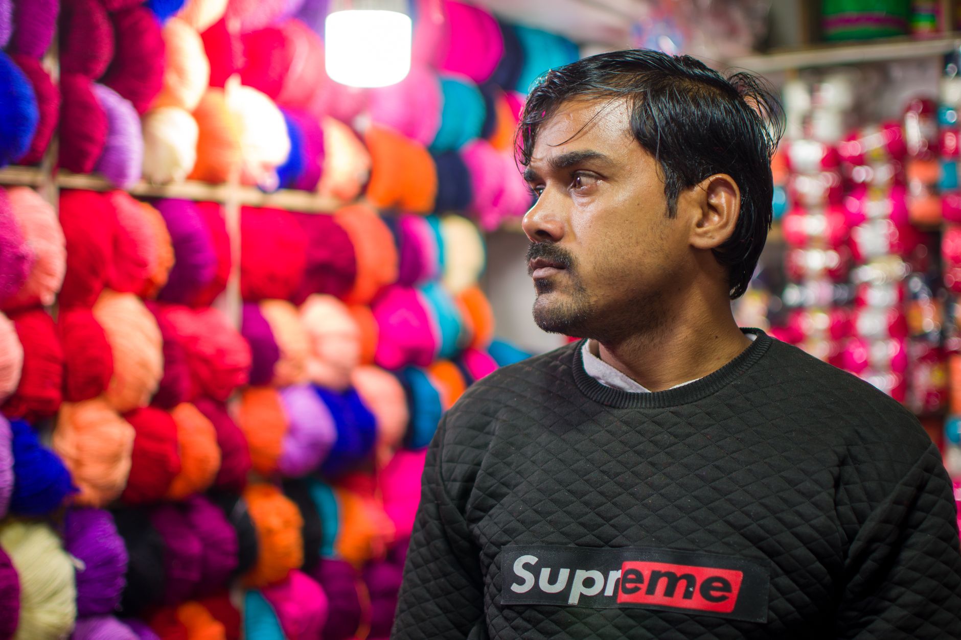 Person standing beside colorful textile rolls
